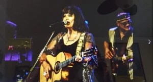 A woman from Sister Sister playing an acoustic guitar.